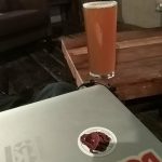 Photo of a KDE Slimbook and a pint